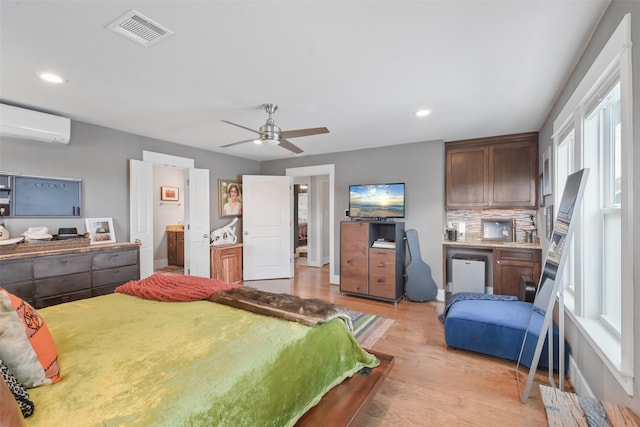 bedroom featuring an AC wall unit, light wood-type flooring, visible vents, and recessed lighting