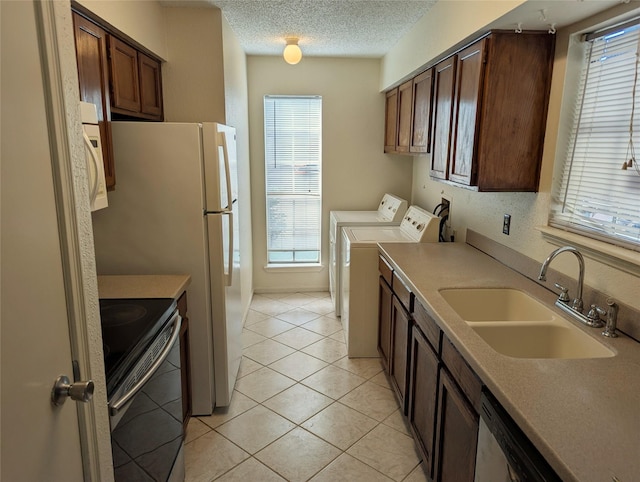 kitchen with sink, light tile patterned floors, washing machine and dryer, a textured ceiling, and stainless steel electric range