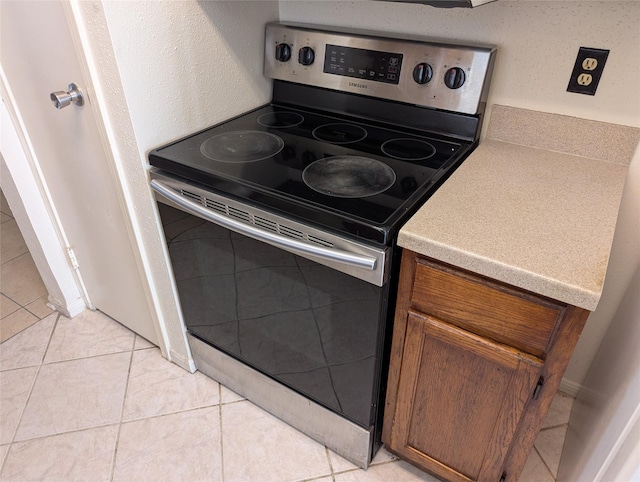 kitchen featuring stainless steel electric stove and light tile patterned flooring