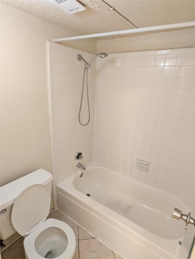 bathroom with tile patterned flooring, tiled shower / bath combo, toilet, and a textured ceiling