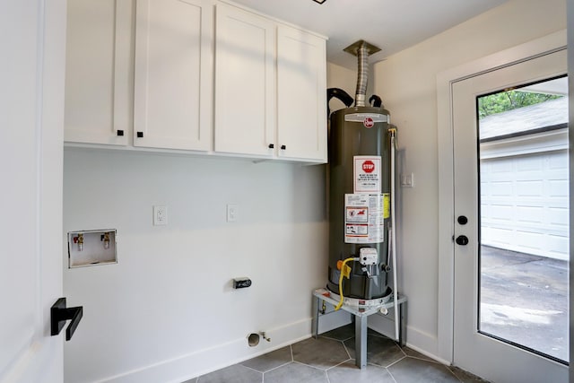 clothes washing area featuring water heater, cabinets, dark tile patterned floors, hookup for a washing machine, and hookup for an electric dryer