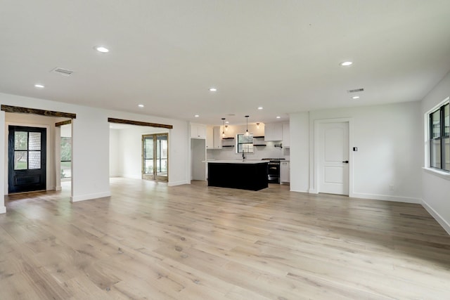 unfurnished living room with french doors, a healthy amount of sunlight, and light hardwood / wood-style flooring