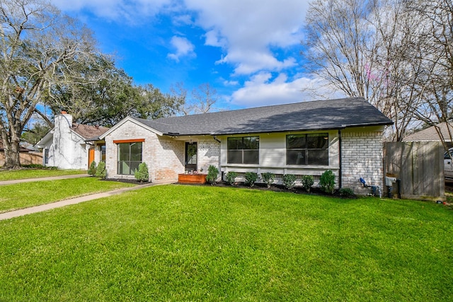 view of front of property featuring a front yard, brick siding, and fence