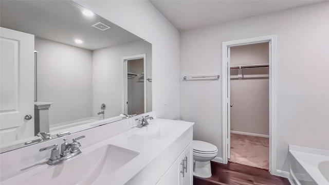 bathroom featuring vanity, hardwood / wood-style flooring, a tub, and toilet