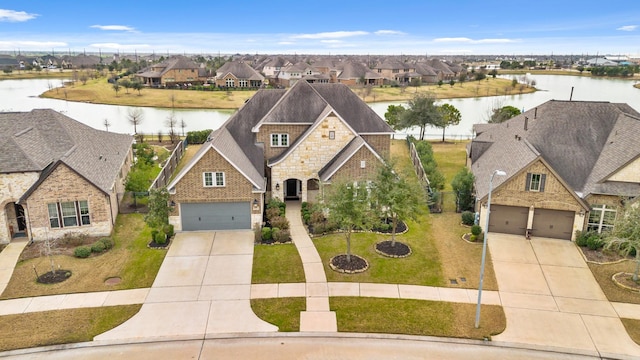 view of front of home with a garage, a front yard, and a water view