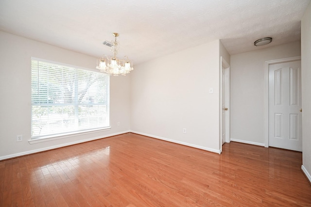 unfurnished room with wood-type flooring, a notable chandelier, and a textured ceiling