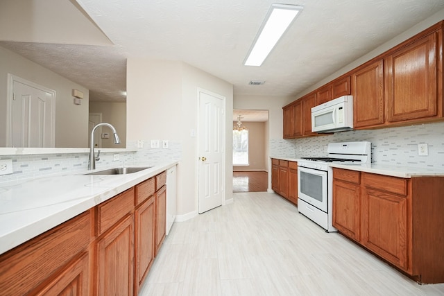 kitchen with a notable chandelier, sink, backsplash, and white appliances
