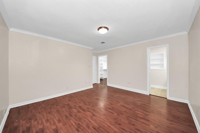 spare room featuring crown molding, built in features, and dark hardwood / wood-style floors