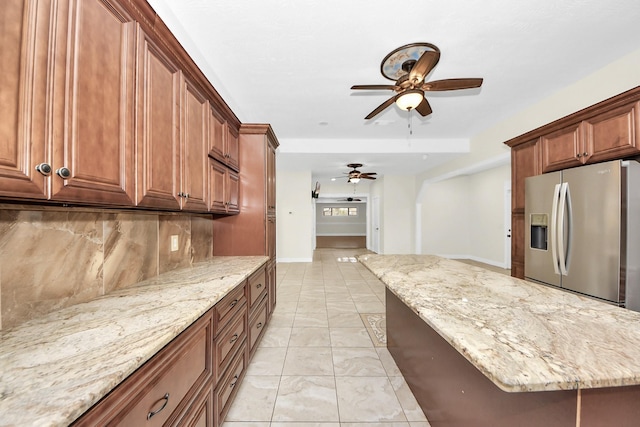 kitchen featuring stainless steel refrigerator with ice dispenser, backsplash, ceiling fan, and light stone counters