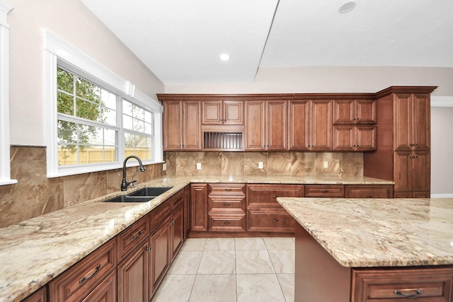 kitchen featuring light stone countertops, sink, and backsplash