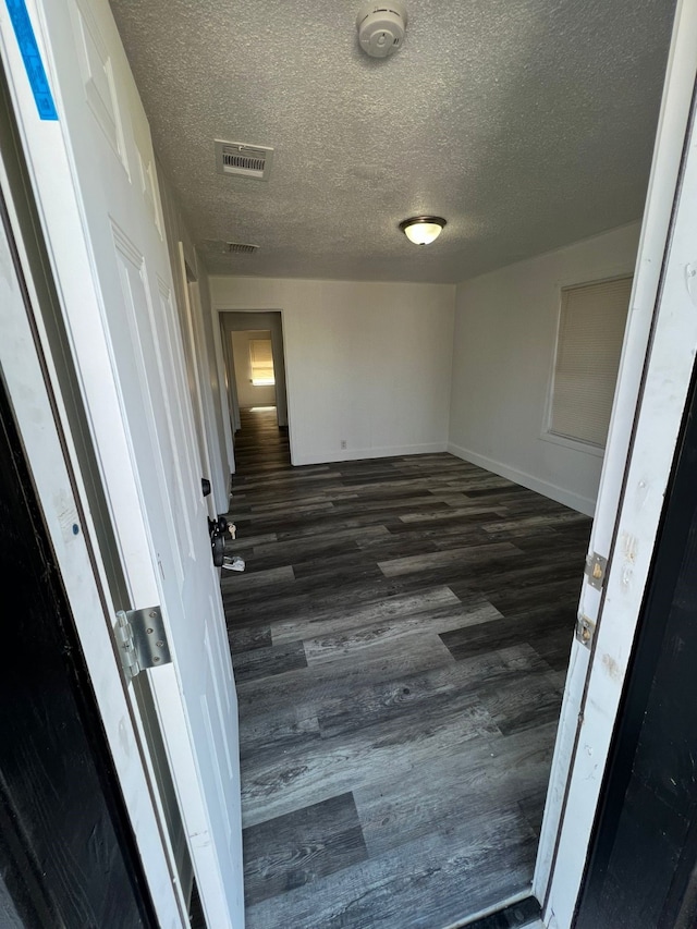 interior space featuring dark wood-type flooring and a textured ceiling