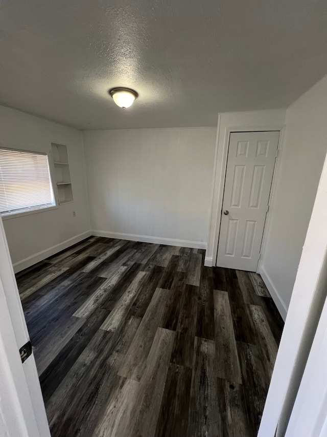 unfurnished room featuring dark hardwood / wood-style flooring and a textured ceiling