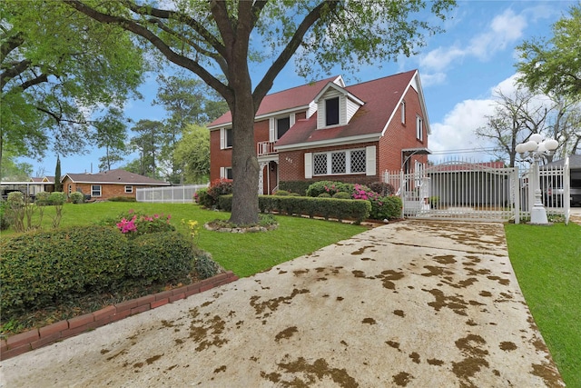 view of front of property with brick siding, a fenced front yard, a front yard, and a gate