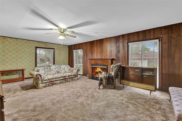 living room featuring light carpet, wallpapered walls, a fireplace with flush hearth, and a ceiling fan