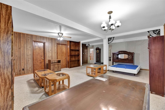 carpeted bedroom with wooden walls, a chandelier, and baseboards
