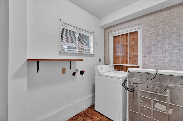 clothes washing area with laundry area, brick patterned floor, baseboards, and washer / dryer