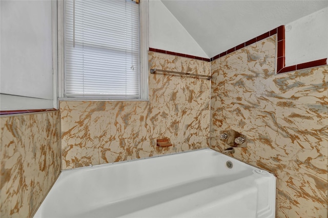 bathroom featuring lofted ceiling, a bath, and wallpapered walls