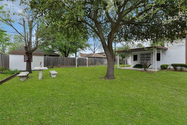 view of yard with a storage shed, a fenced backyard, and an outdoor structure