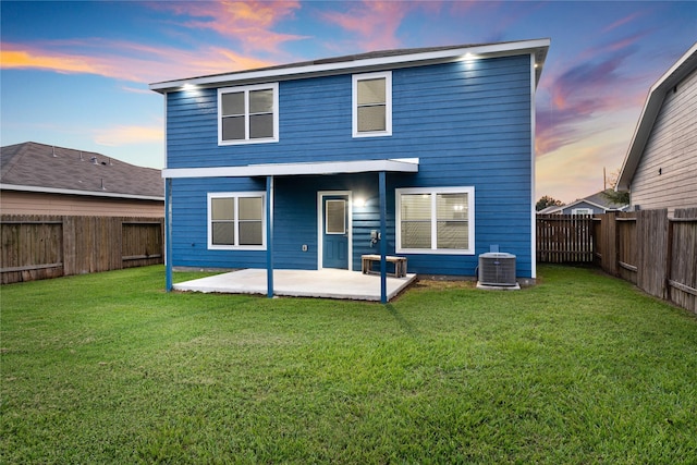 back house at dusk with cooling unit, a lawn, and a patio area