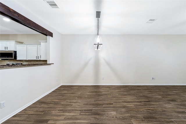 unfurnished dining area featuring dark hardwood / wood-style flooring and beam ceiling