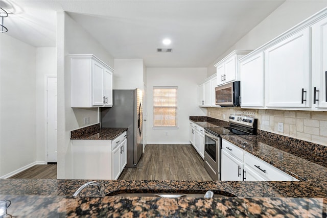 kitchen featuring white cabinetry, appliances with stainless steel finishes, dark stone countertops, and decorative backsplash