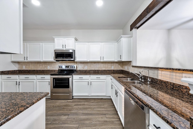 kitchen featuring dark stone countertops, stainless steel appliances, sink, and white cabinets