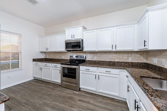 kitchen with appliances with stainless steel finishes, dark hardwood / wood-style floors, white cabinets, and decorative backsplash