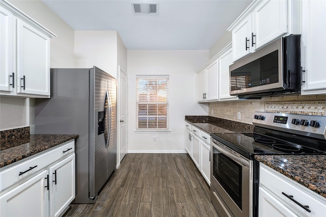 kitchen featuring appliances with stainless steel finishes, dark stone counters, and white cabinets