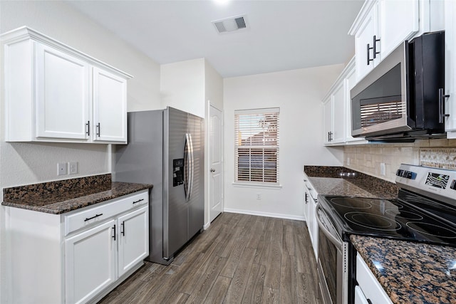 kitchen featuring dark wood-type flooring, appliances with stainless steel finishes, dark stone countertops, tasteful backsplash, and white cabinets