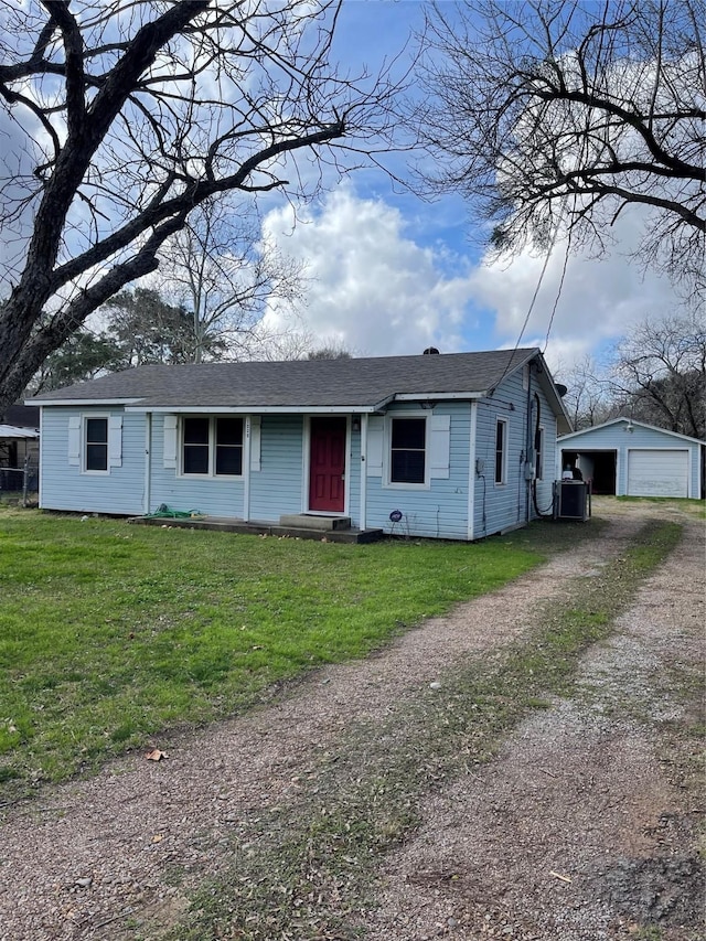 view of front of property featuring an outbuilding, a garage, a front yard, and central air condition unit