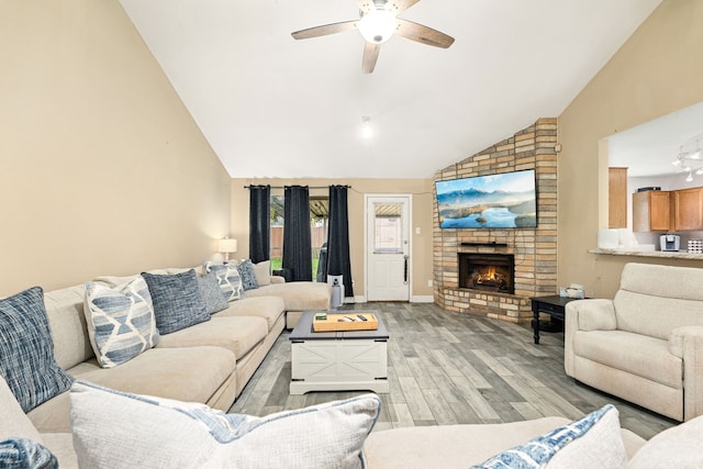 living room featuring a fireplace, high vaulted ceiling, ceiling fan, and light wood-type flooring