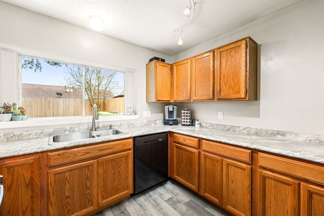 kitchen with sink, light hardwood / wood-style flooring, black dishwasher, track lighting, and light stone countertops