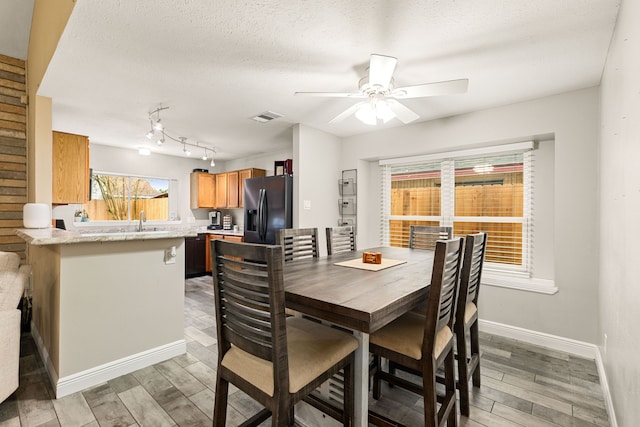 dining area featuring sink, a textured ceiling, and ceiling fan