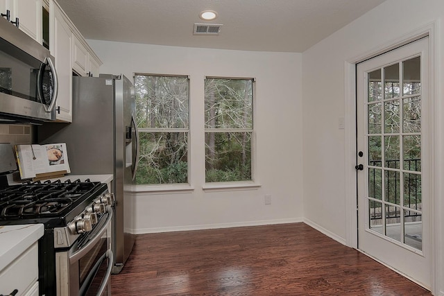 kitchen with appliances with stainless steel finishes, dark hardwood / wood-style floors, white cabinets, backsplash, and a textured ceiling