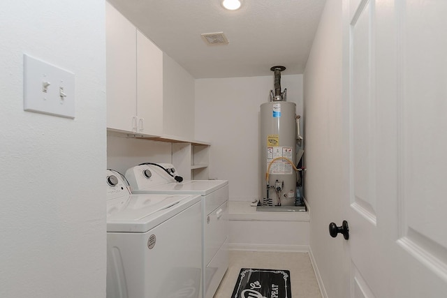 laundry room with water heater, cabinets, and washer and clothes dryer