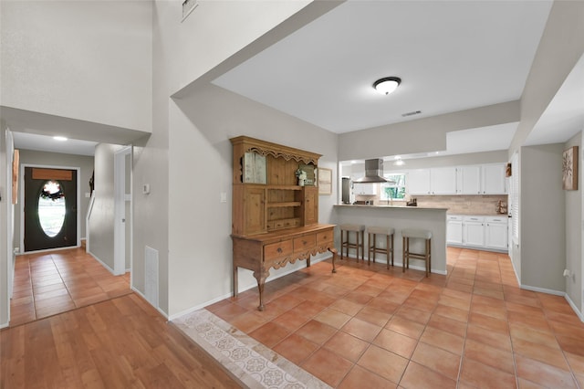 kitchen featuring extractor fan, backsplash, white cabinets, a kitchen breakfast bar, and kitchen peninsula