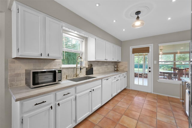 kitchen with white cabinetry, sink, white dishwasher, and decorative backsplash