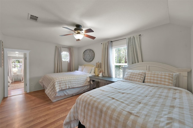 bedroom featuring ceiling fan, lofted ceiling, multiple windows, and light wood-type flooring