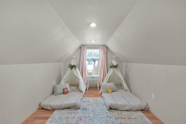 living area with vaulted ceiling, a textured ceiling, and light wood-type flooring