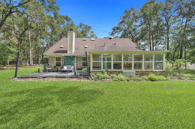 rear view of house with a yard, a patio area, and a sunroom