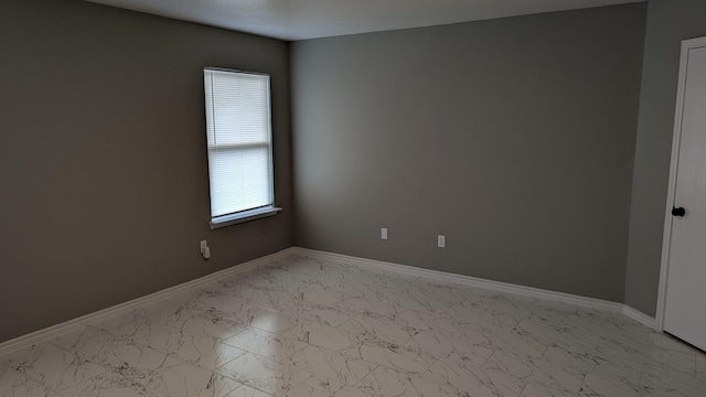 unfurnished room with marble finish floor and baseboards