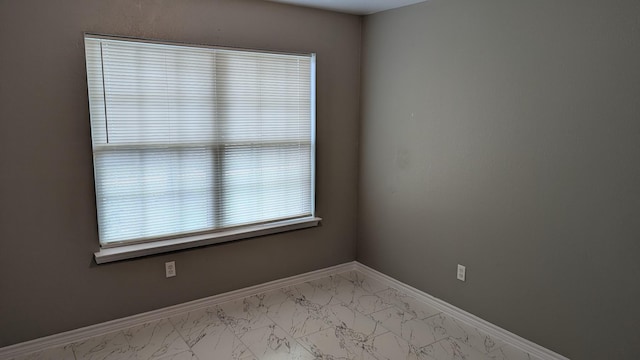 empty room featuring marble finish floor and baseboards