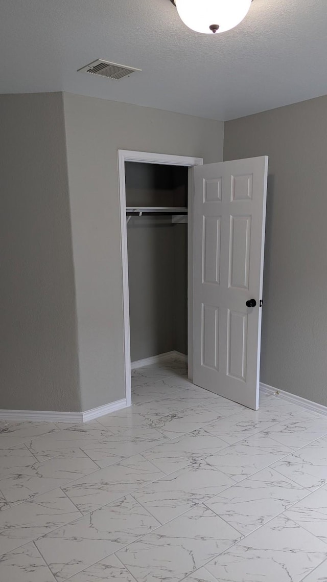 unfurnished bedroom with marble finish floor, visible vents, and baseboards