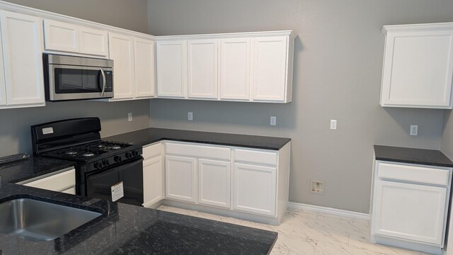 kitchen with baseboards, stainless steel microwave, marble finish floor, black gas stove, and white cabinetry