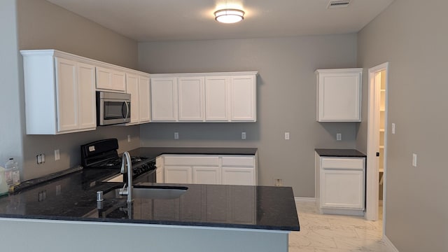 kitchen featuring a peninsula, white cabinetry, marble finish floor, black range with gas stovetop, and stainless steel microwave