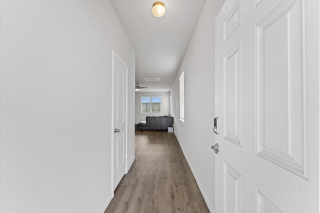 hallway with light wood-type flooring, visible vents, and baseboards