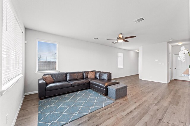 living room with baseboards, wood finished floors, visible vents, and a ceiling fan