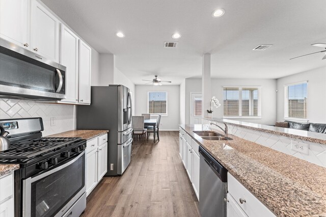 kitchen with white cabinetry, appliances with stainless steel finishes, light stone counters, and a sink