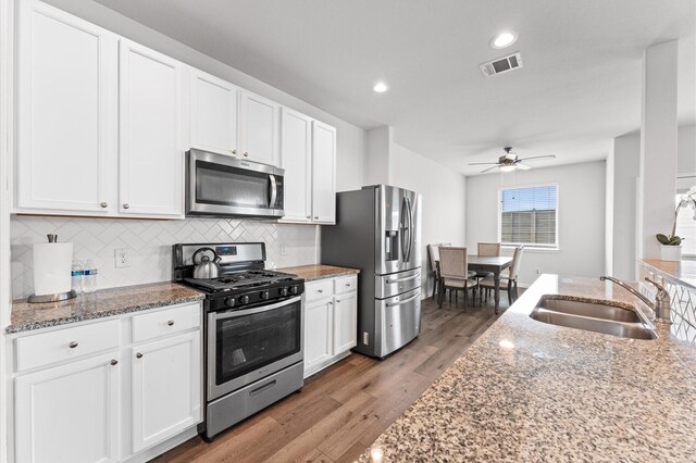 kitchen featuring light stone counters, a sink, visible vents, white cabinetry, and appliances with stainless steel finishes