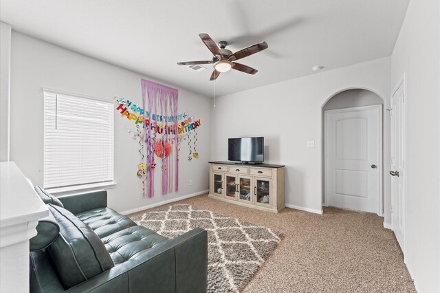 carpeted living area with ceiling fan, arched walkways, and baseboards